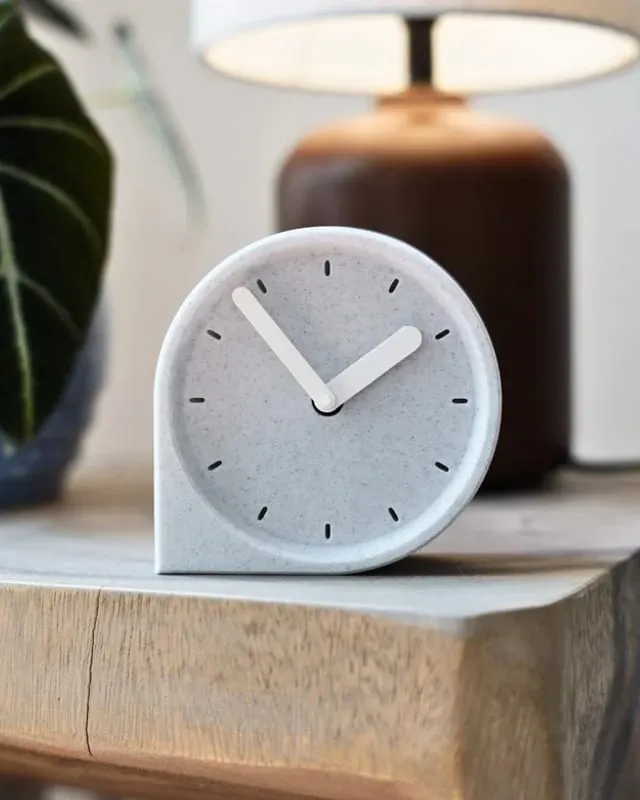 Cove Clock, a rounded stone-finish table clock on an oak ledge